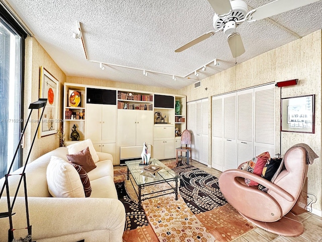 living room with ceiling fan, a textured ceiling, and track lighting