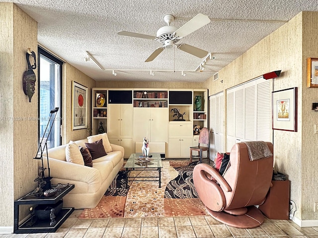 tiled living room featuring rail lighting, ceiling fan, and a textured ceiling