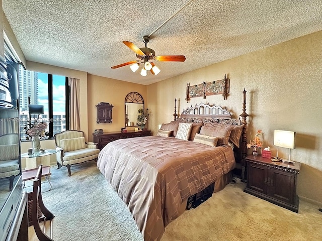 bedroom featuring ceiling fan, light colored carpet, and a textured ceiling