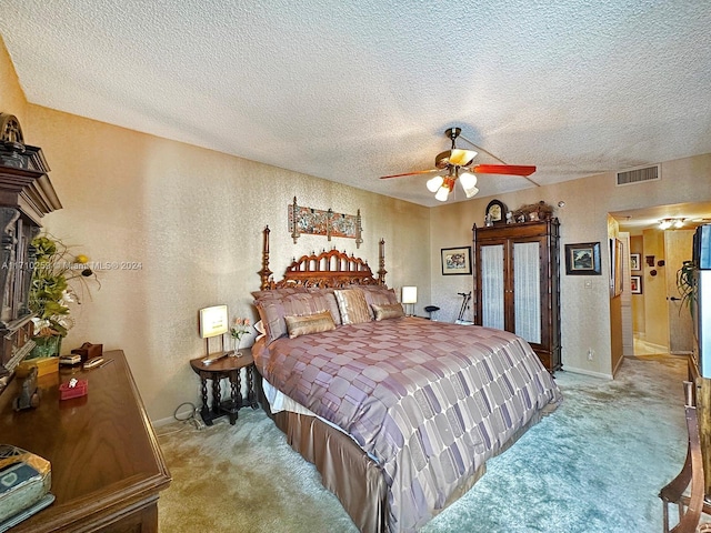 carpeted bedroom featuring ceiling fan and a textured ceiling