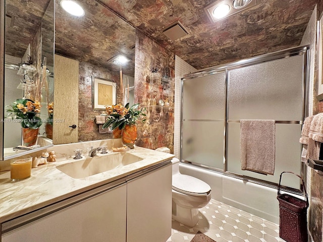 full bathroom with vanity, bath / shower combo with glass door, and toilet