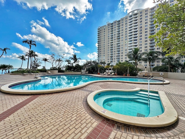 view of pool with a hot tub and a patio area