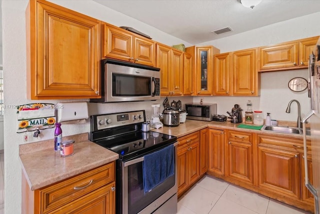 kitchen featuring light tile patterned flooring, sink, and appliances with stainless steel finishes