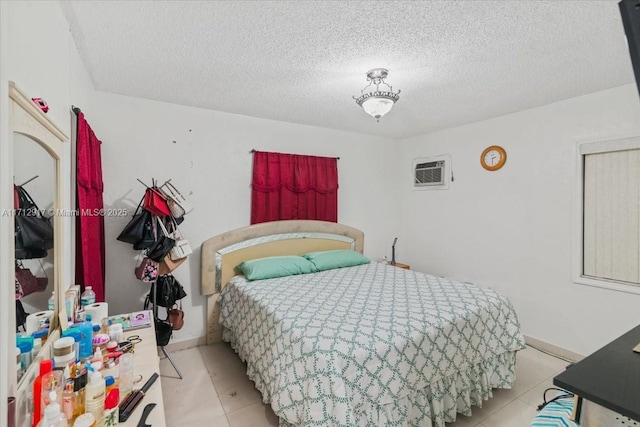 bedroom with light tile patterned floors, a textured ceiling, and a wall unit AC