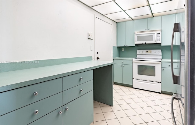 kitchen with a paneled ceiling, light tile patterned floors, and white appliances