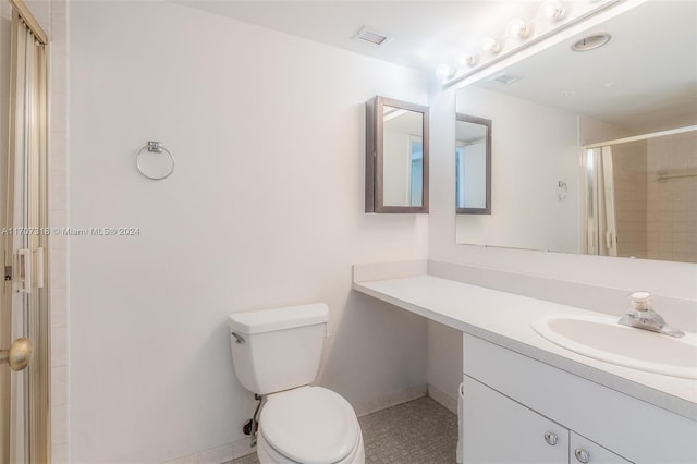 bathroom with tile patterned floors, vanity, a shower with shower door, and toilet