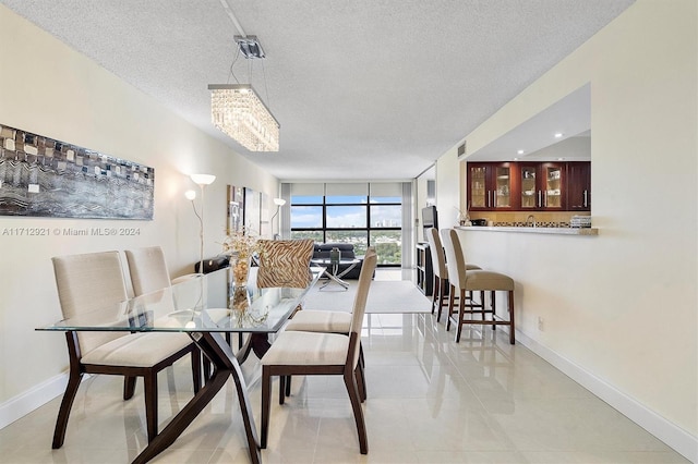 dining area with light tile patterned floors, a textured ceiling, expansive windows, and a notable chandelier