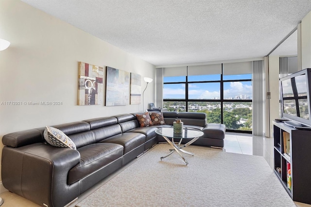 living room featuring a wall of windows, a textured ceiling, and light tile patterned floors