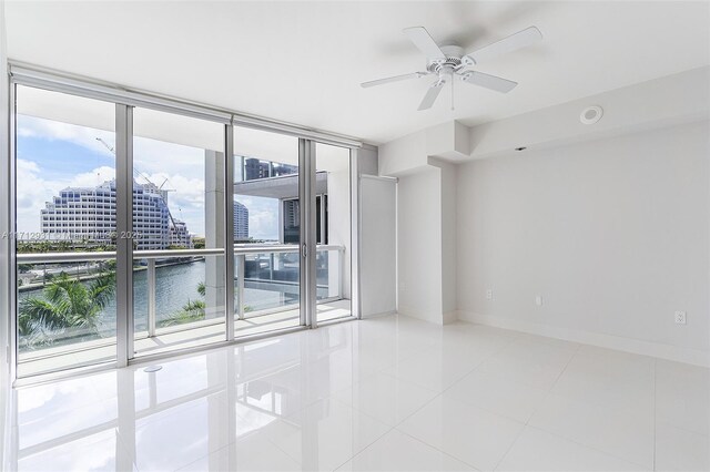 495 Brickell Ave Unit Bay407, Miami, FL 33131 - empty room featuring tile patterned flooring, baseboards, ceiling fan, floor to ceiling windows, and a water view