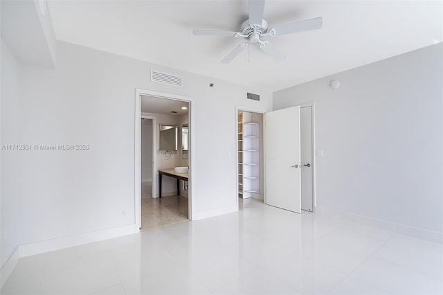 unfurnished bedroom featuring light tile patterned floors, ensuite bathroom, visible vents, and baseboards