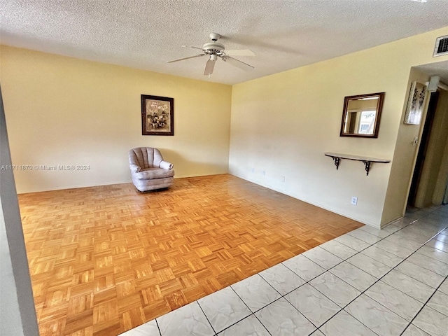 spare room with ceiling fan, light parquet flooring, and a textured ceiling