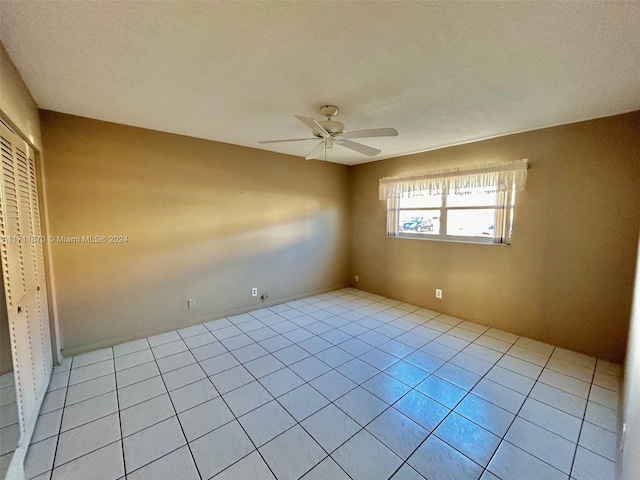 spare room featuring ceiling fan, light tile patterned floors, and a textured ceiling