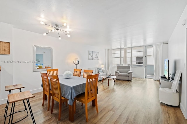 dining room with a notable chandelier, baseboards, and wood finished floors