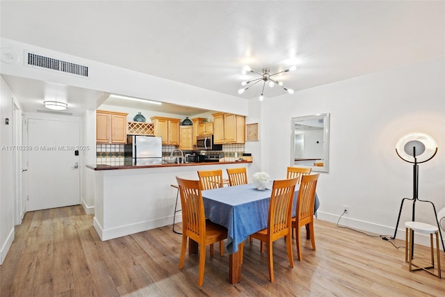 dining area featuring light wood-style floors, visible vents, baseboards, and an inviting chandelier