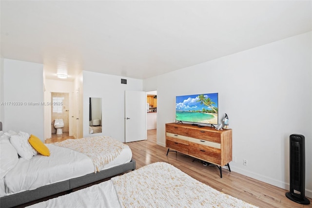 bedroom featuring light wood finished floors, connected bathroom, visible vents, and baseboards