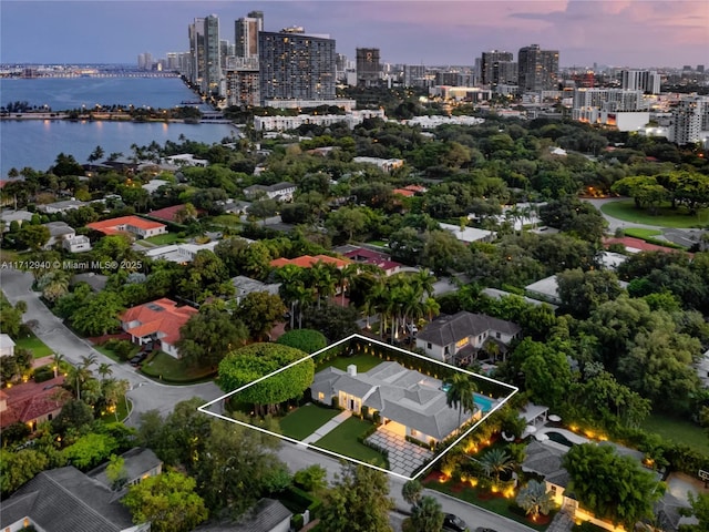 aerial view at dusk featuring a water view and a view of city