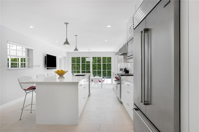 kitchen featuring white cabinets, decorative light fixtures, a center island, and high end appliances