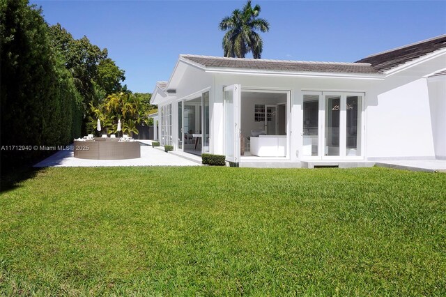 back of house featuring a sunroom, a patio, a yard, and an outdoor hangout area