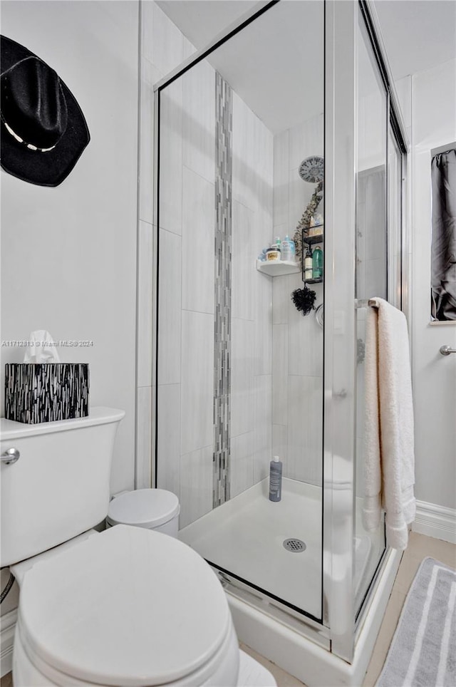 bathroom featuring toilet and a shower with shower door