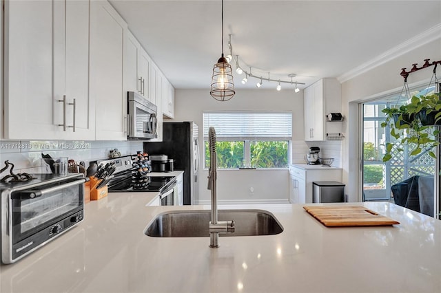 kitchen with white cabinetry, sink, stainless steel appliances, backsplash, and decorative light fixtures