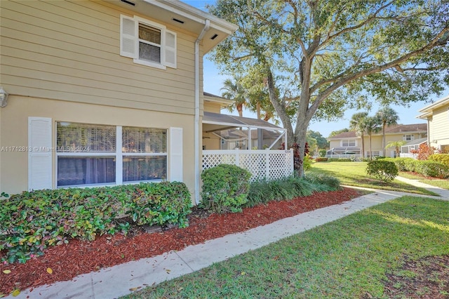 view of home's exterior featuring a yard and glass enclosure