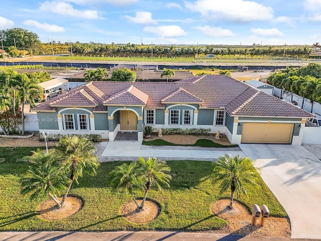 mediterranean / spanish home featuring a garage, a tiled roof, driveway, and stucco siding