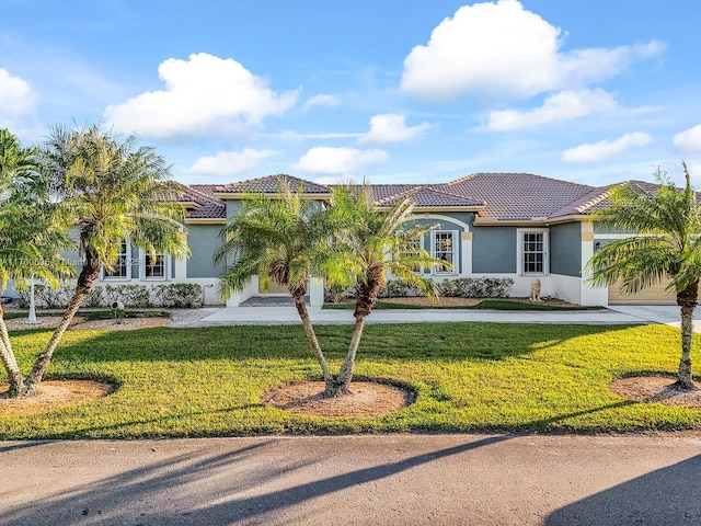 mediterranean / spanish-style home with concrete driveway, a front lawn, and stucco siding