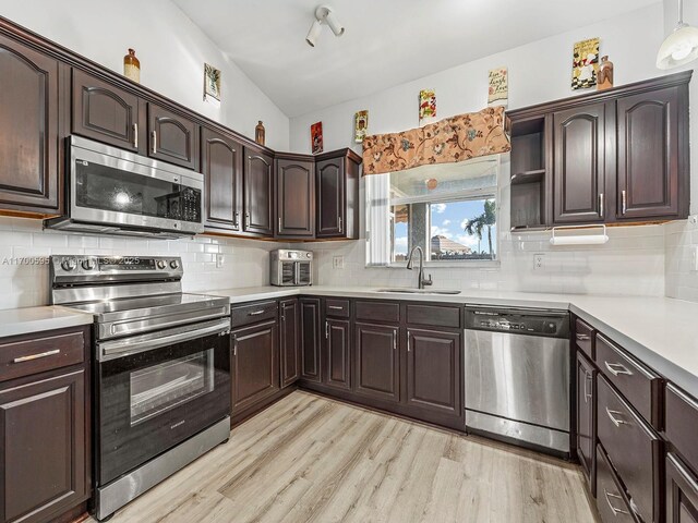 kitchen featuring light wood-type flooring, decorative backsplash, appliances with stainless steel finishes, and sink