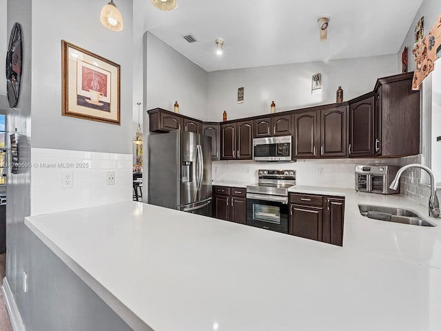 kitchen with visible vents, appliances with stainless steel finishes, a sink, dark brown cabinets, and a peninsula