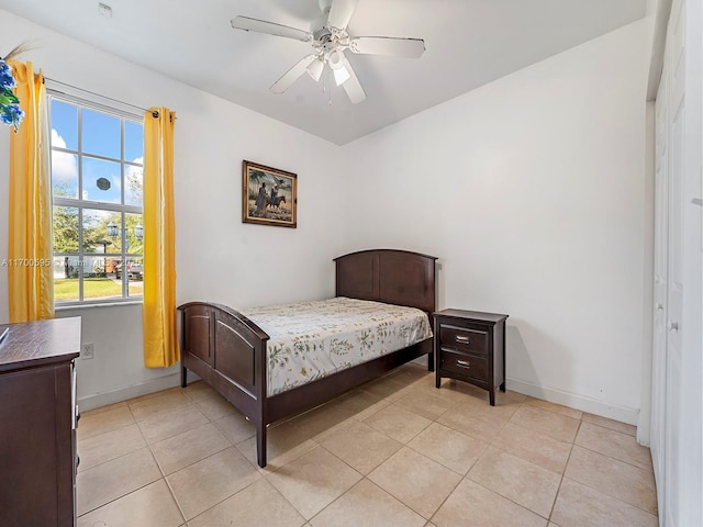 bedroom featuring light tile patterned floors, baseboards, and a ceiling fan