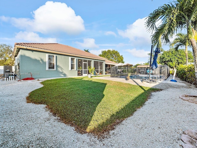 back of property with a fenced in pool, a sunroom, a tiled roof, a yard, and stucco siding