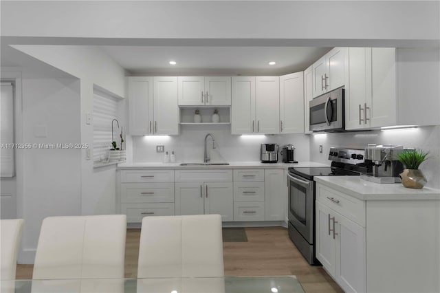 kitchen featuring white cabinetry, sink, stainless steel appliances, and light hardwood / wood-style flooring