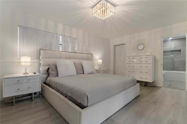 bedroom featuring a chandelier, light hardwood / wood-style flooring, and ensuite bath