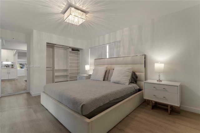 bedroom featuring light wood-type flooring and an inviting chandelier