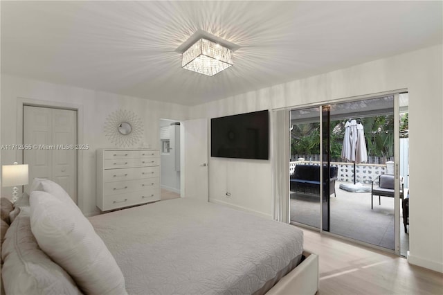 bedroom with wood-type flooring, access to outside, and an inviting chandelier