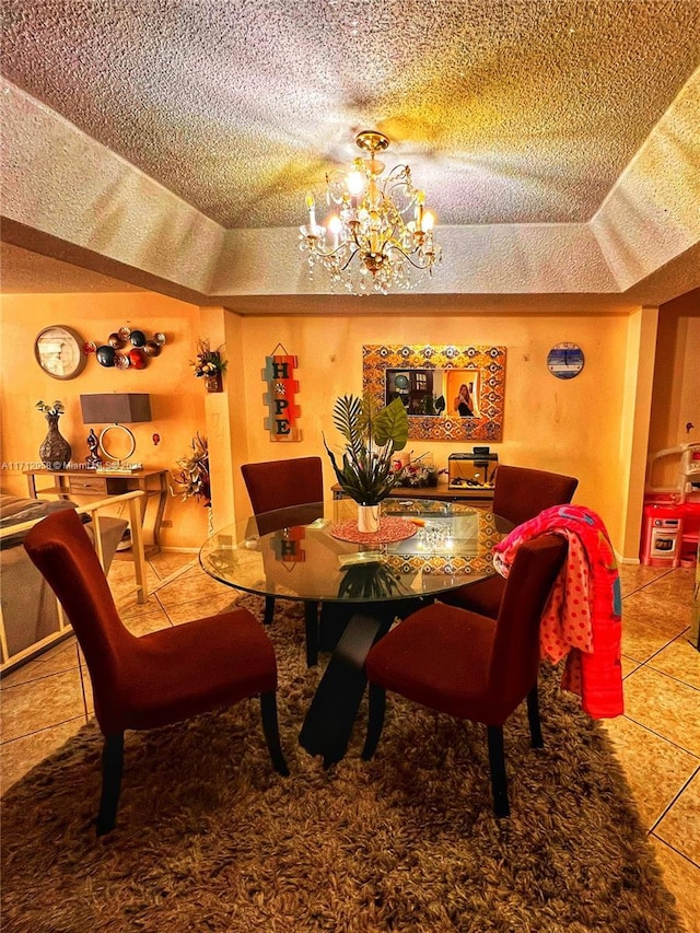 tiled dining room featuring a tray ceiling, a textured ceiling, and a notable chandelier