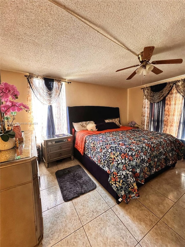 bedroom with ceiling fan, light tile patterned floors, and a textured ceiling