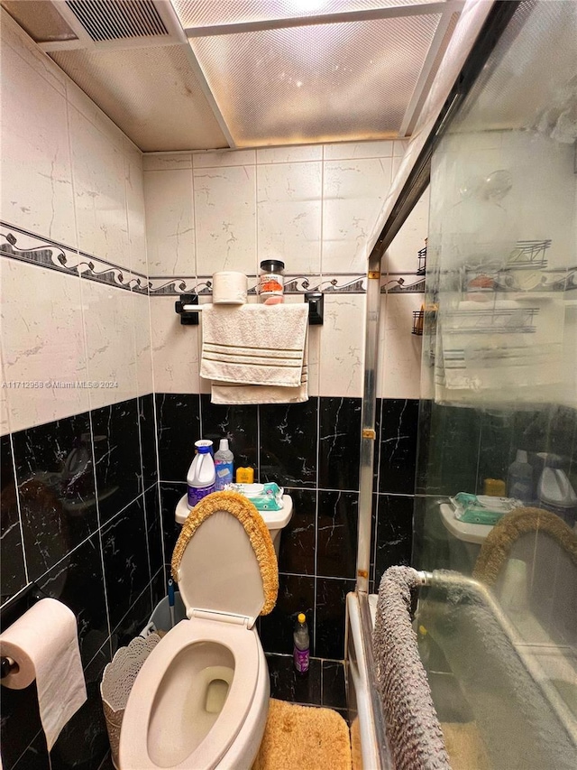 bathroom featuring toilet, tile walls, and walk in shower