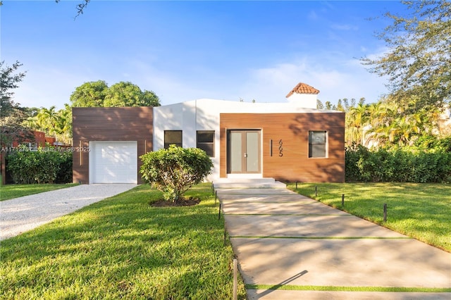 view of front of home featuring an attached garage, gravel driveway, and a front lawn