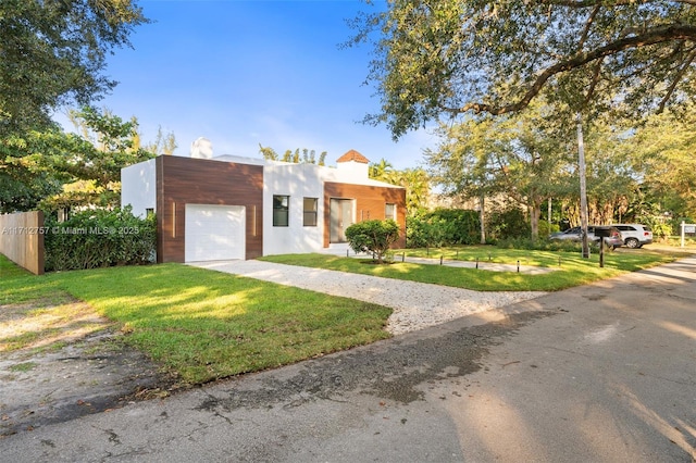 view of front of house with an attached garage, driveway, a front yard, and fence