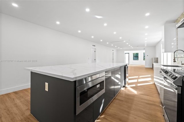 kitchen with dark cabinetry, a center island, light wood-style floors, and stainless steel appliances