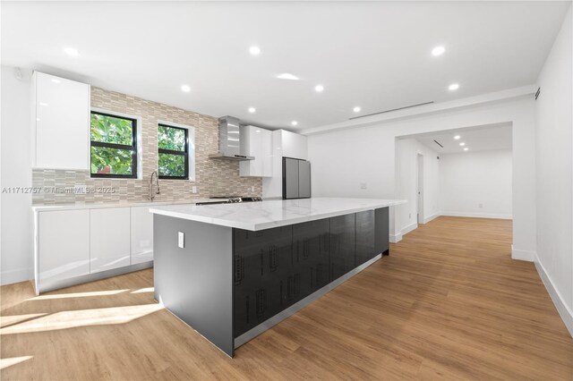 665 NE 117th St, Biscayne Park, FL 33161 - kitchen with wall chimney range hood, fridge, a center island, white cabinetry, and modern cabinets