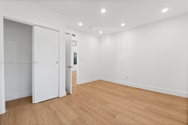 unfurnished bedroom with light wood-style flooring, recessed lighting, baseboards, and a closet