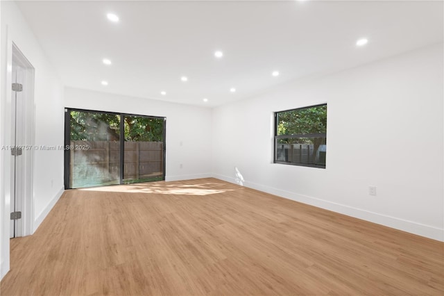 spare room with recessed lighting, baseboards, plenty of natural light, and light wood-style flooring