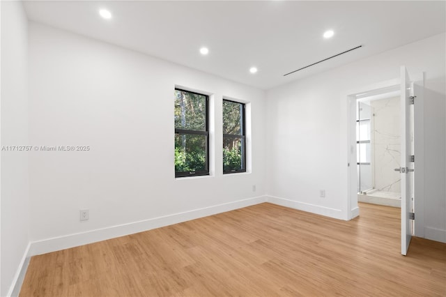 empty room featuring recessed lighting, baseboards, and light wood finished floors