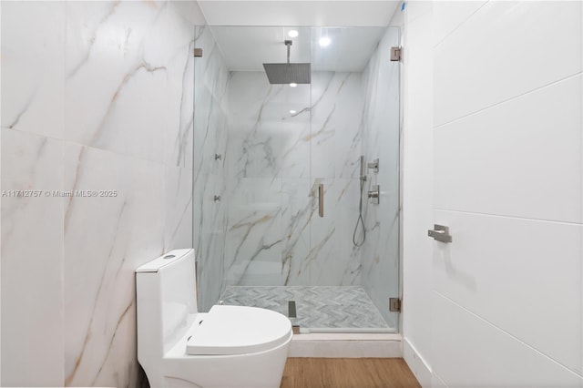 bathroom featuring a marble finish shower, toilet, and wood finished floors