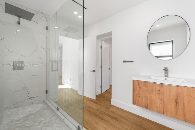 full bathroom featuring a marble finish shower, baseboards, recessed lighting, wood finished floors, and vanity