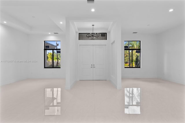 foyer entrance featuring a chandelier, light tile patterned floors, and plenty of natural light