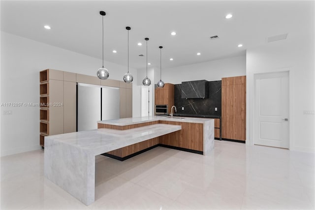 kitchen featuring tasteful backsplash, light stone counters, a spacious island, and decorative light fixtures