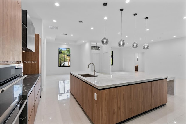 kitchen with sink, hanging light fixtures, a large island, and stainless steel oven